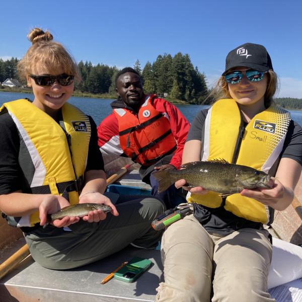 Three VIU students in a boat holding fish